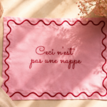 Geborduurde placemat uit de Magritte-lijn van Petites Pièces met surrealistische tekst.